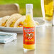 A close up of a bottle of Marie Sharp's Pineapple Habanero hot sauce on a table with tacos.