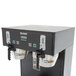 A black Bunn BrewWISE commercial coffee machine on a counter with two silver cups.