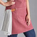 A woman wearing an Acopa Hazleton wine canvas bib apron holding two towels.