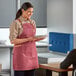 A woman wearing an Acopa Hazleton wine canvas bib apron serving food to a woman.