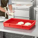 A person wearing gloves in a kitchen using a red Baker's Mark dough proofing box to hold dough.