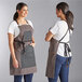 A woman wearing a brown Backyard Pro Smoke grilling apron with utility pockets.
