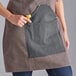 A woman wearing a brown Backyard Pro grilling apron with utility pockets.