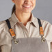 A woman wearing a grey apron with Acopa Hazleton black cross-back straps.