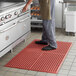 A person standing on a red Choice Cross rubber anti-fatigue mat in a kitchen.