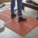 A person standing on a red Choice Cross rubber anti-fatigue mat.