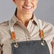 A woman wearing a black Acopa canvas cross-back bib apron.