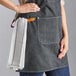 A woman wearing a black Acopa Hazleton canvas bib apron with three pockets.