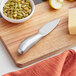 An Acopa stainless steel cheese spade on a cutting board.