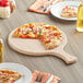 A pizza on a Choice wooden serving board with a knife.