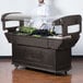 A man in a white coat and gloves standing behind a Carlisle Maximizer Portable Salad Bar on a counter full of food.