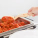 A person using a Cambro beige salad bar spoon to serve food.