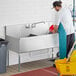 A man washing a Regency utility sink with two compartments on a counter.