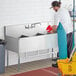 A man cleaning a Regency stainless steel utility sink.