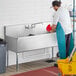 A man cleaning a Regency stainless steel utility sink.