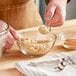 A person using Choice stainless steel measuring spoons to pour brown powder into a bowl.