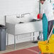 A man washing a Regency stainless steel utility sink.