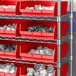 A white industrial shelf with red Regency shelf bins.