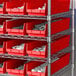 A red and silver shelving unit with a red bin full of white objects.