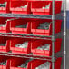 A metal shelving unit with red Regency shelf bins containing white objects.