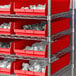 A shelf with Regency red plastic bins holding white objects.