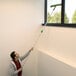 A man uses an Unger OptiLoc telescopic pole to clean a window.