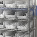 A metal shelving unit with clear plastic Regency shelf bins.