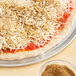 A pizza with cheese and Regal ground oregano leaves on it.