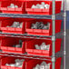 A metal shelving unit with red Regency shelf bins filled with white objects.