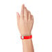 A person holding a red Carnival King wristband.