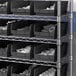 A metal shelving unit with black Regency shelf bins filled with objects.