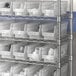 A white plastic shelf bin from Regency on a metal shelf.