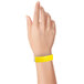 A close-up of a hand wearing a yellow Carnival King wristband.