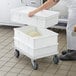 A woman holding a white Baker's Mark dough proofing container with dough inside.