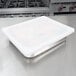 A white plastic lid on a stainless steel Vollrath steam table pan.