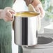 A person in gloves holding a Choice stainless steel bain marie pot of soup.