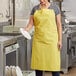 A woman wearing a yellow Choice vinyl apron holding a white plate.