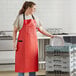A woman in a red Choice vinyl apron and gloves holding a plate.
