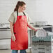 A woman in a Choice red vinyl apron holding a plate in a kitchen.