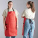 Two women wearing red Choice vinyl aprons over jeans.