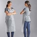 Two women wearing Choice clear vinyl aprons standing on a counter in a professional kitchen.