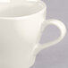 A close-up of a Tuxton Europa white cappuccino mug with a handle.