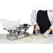 A person using a Cardinal Detecto stainless steel baker's dough scale to weigh dough in a white bowl.