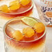Two glasses of drink garnished with Fabbri Candied Ginger and lime wedges on a table.