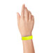 A hand holding a yellow Carnival King wristband.