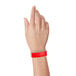 A woman's hand holding a red Carnival King Tyvek wristband.