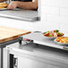 A man using a Metro stainless steel countertop shelf warmer to prepare food on a counter in a professional kitchen.