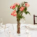 A Libbey flute glass used as a vase with pink roses on a restaurant table.