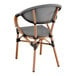 A Lancaster Table & Seating black and white outdoor arm chair with a wicker back and wooden frame.