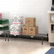 A Regency black epoxy dunnage shelf in a kitchen with boxes and bottles on it.